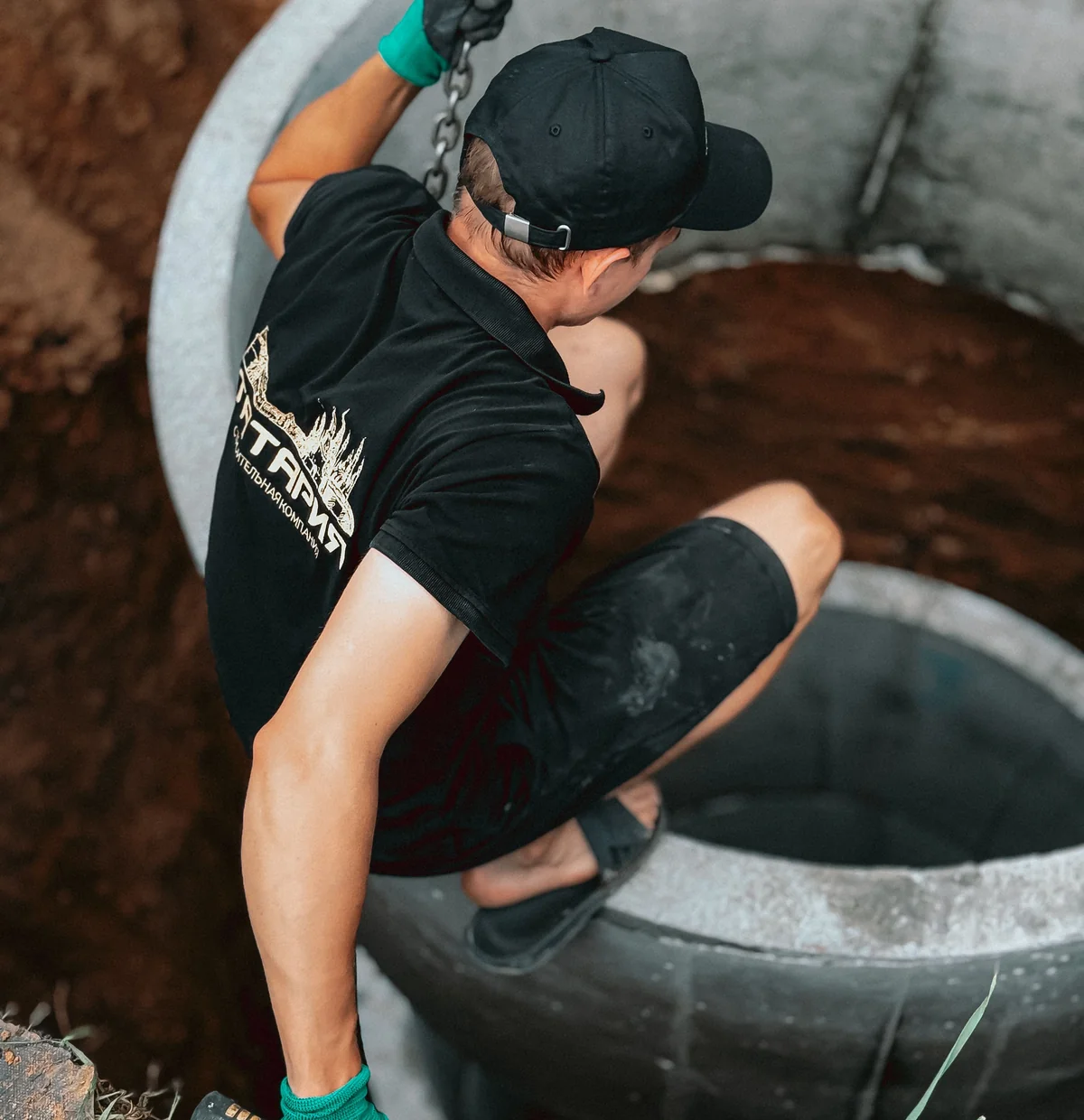 Pose d'une cuve en fouille, mains gantées sur l'anneau en béton